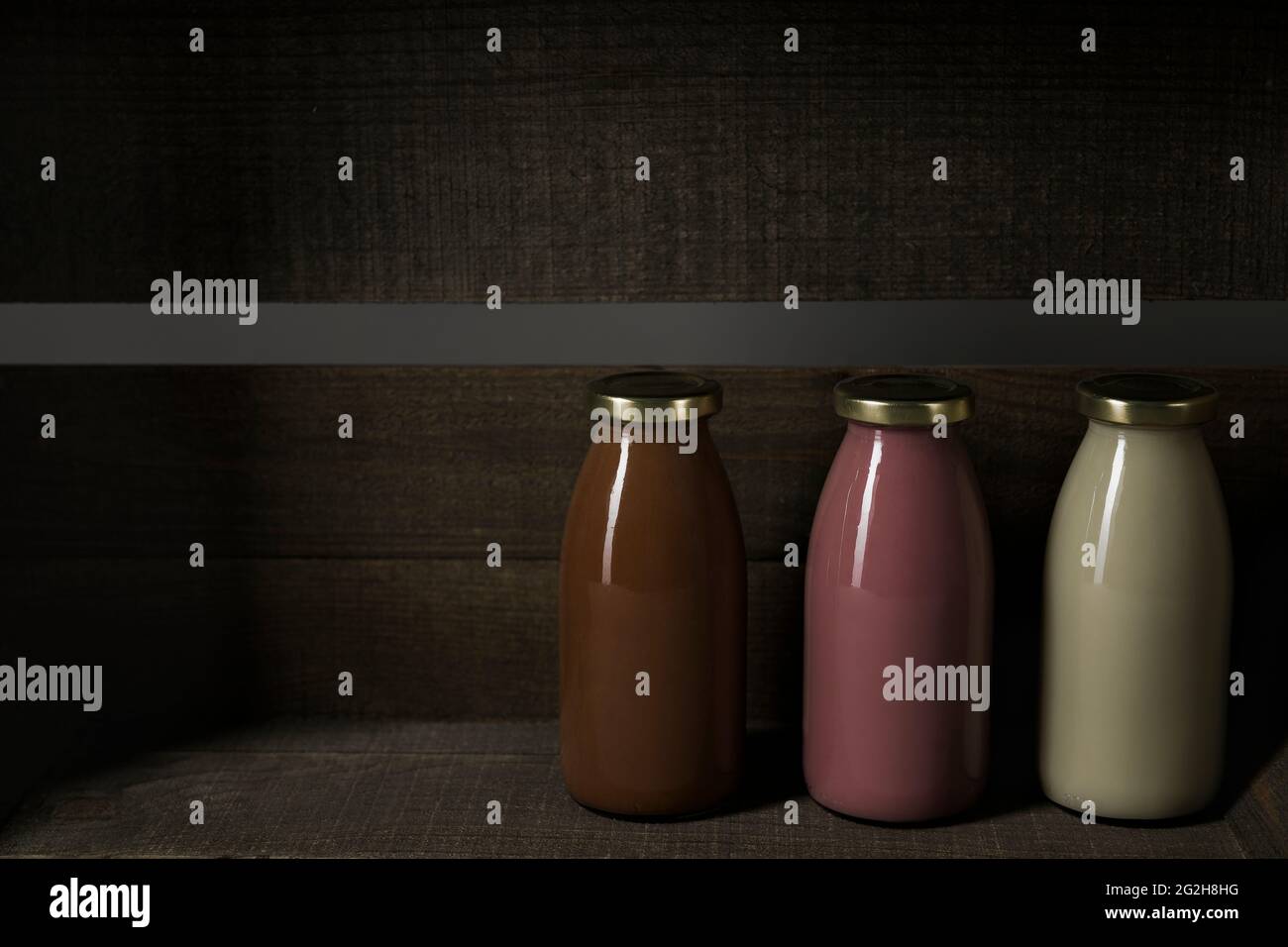 Lait au chocolat, lait de fraise, lait d'avoine, caisse de fruits, bois Banque D'Images