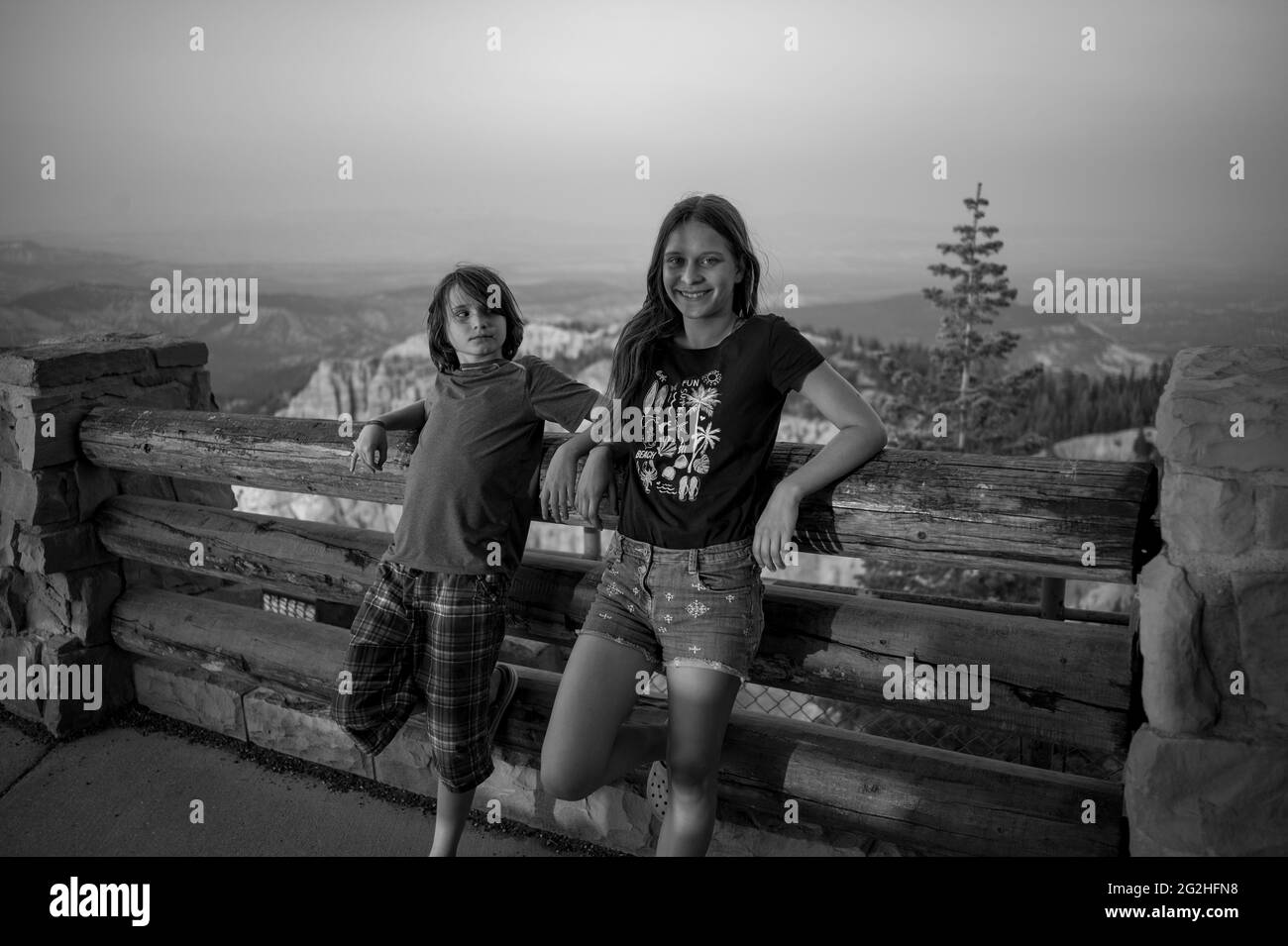 Fille et garçon profitant du coucher du soleil depuis Rainbow point - un parc national avec des falaises rouges et roses et des formations rocheuses, forêt d'épicéa et de sapin et sentiers de randonnée. Parc national de Bryce Canyon, Utah, États-Unis, Banque D'Images
