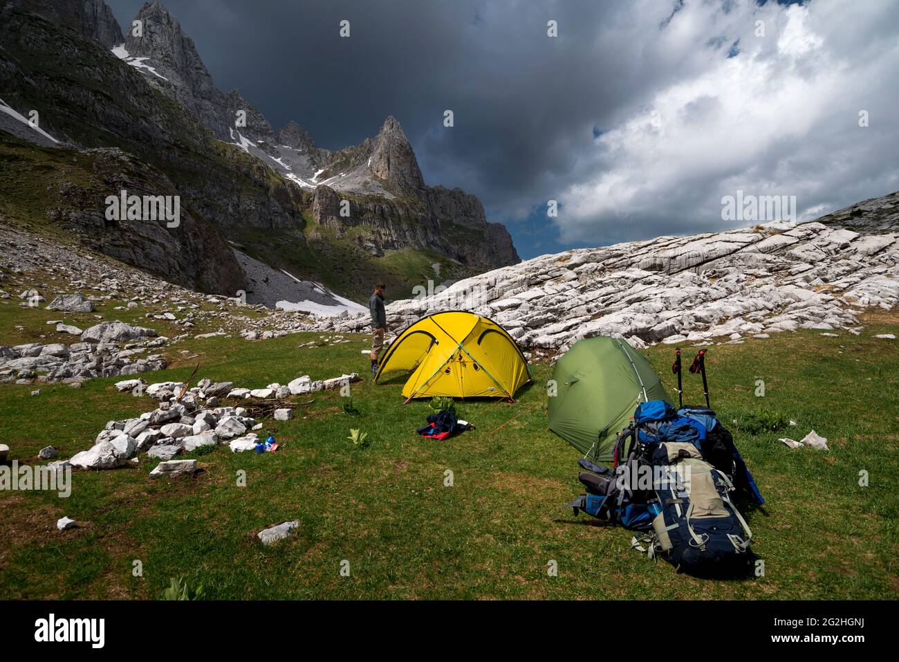 Un seul randonneur est doté de deux tentes et de matériel de randonnée en face des montagnes du parc national de Prokletije sous un ciel spectaculaire Banque D'Images