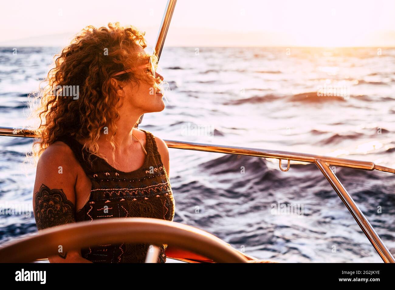 Femme adulte riche appréciez le style de vie de luxe voyageant sur voilier pour les vacances d'été - jolie femme personnes en plein air liberté avec l'océan autour de la mer au coucher du soleil Banque D'Images
