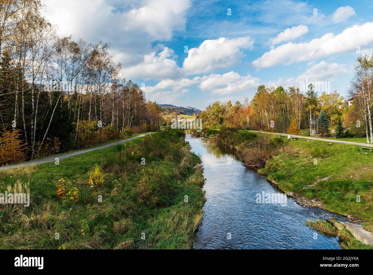 Paysage d'automne avec rivière, sentier et route étroite, arbres colorés et petites collines sur le fond près du village Brenna en Pologne Banque D'Images