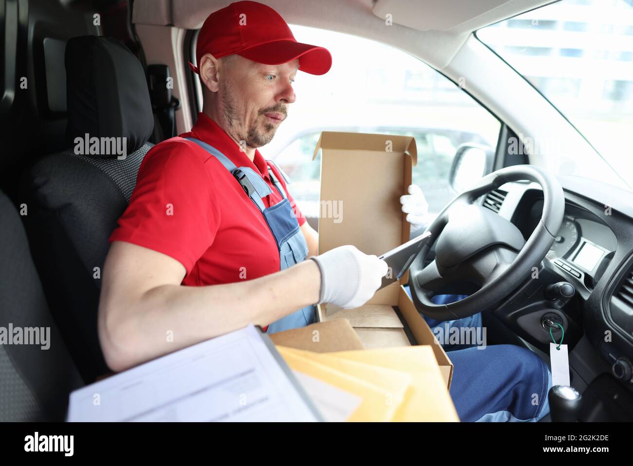 Surprise de la part d'un messager qui a sorti la tablette numérique de sa boîte en carton Banque D'Images Surprise de la part d'un messager qui a sorti la tablette numérique de sa boîte en carton Banque D'Images