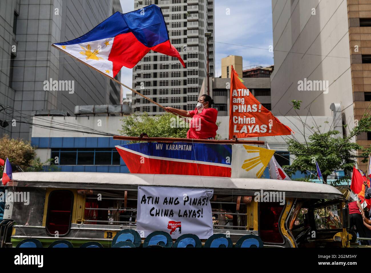 Metro Manille, Philippines. 12 juin 2021. Un activiste hante un drapeau philippin devant le consulat chinois lors d'une manifestation pour marquer le jour de l'indépendance dans le quartier financier de Makati. Divers groupes ont appelé la Chine à mettre fin à ses activités maritimes dans la mer de Chine méridionale contestée, qui met en danger la paix et la stabilité dans la région. Crédit : CIC de la majorité mondiale/Alamy Live News Banque D'Images