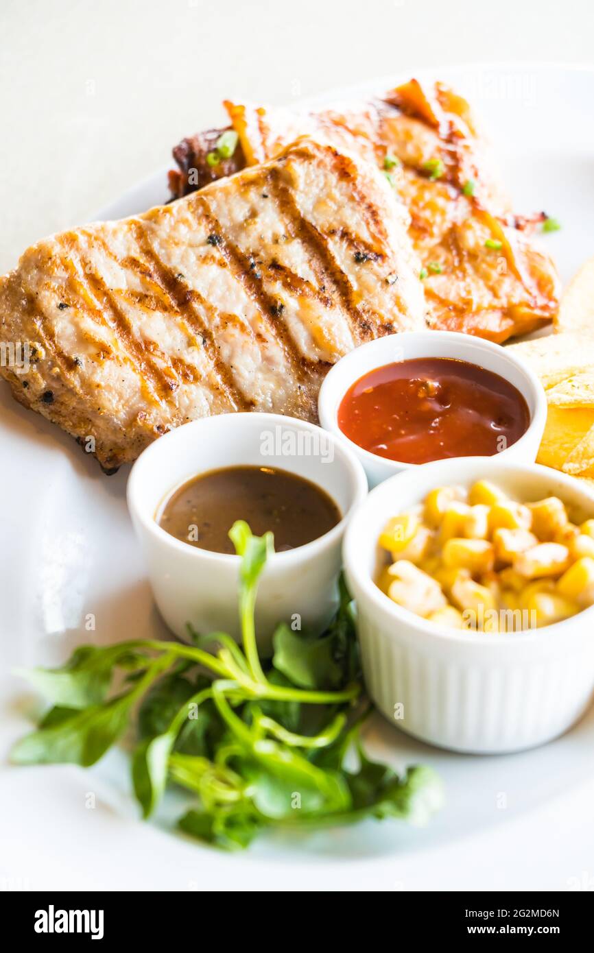 Côte de porc et de poulet steak avec frites et sauce en plaque blanche Banque D'Images