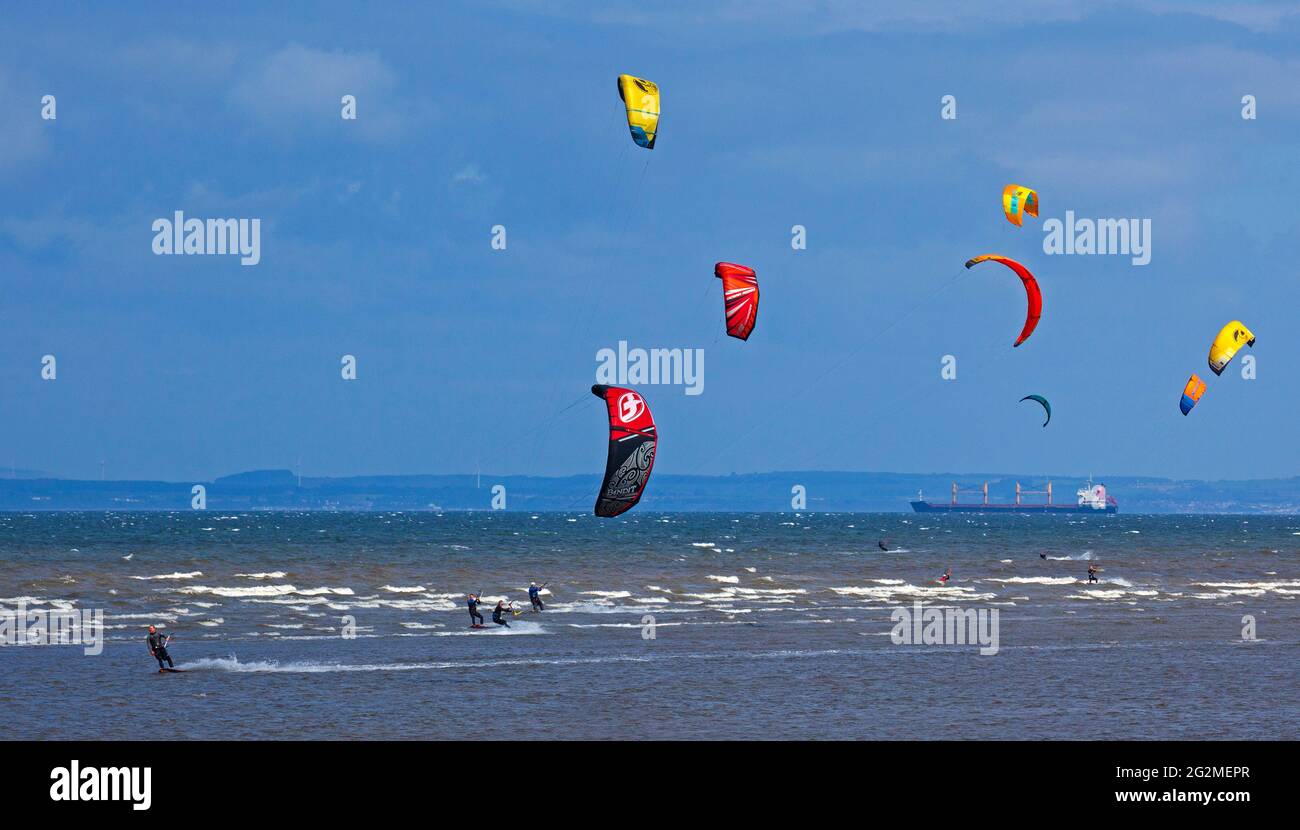 Longniddry, East Lothian, Écosse, météo britannique. 12 juin 2021. Vents de 24 km/h potentiels rafales de 35 km/h avec le soleil et les nuages qui semblaient être le temps parfait pour plus de 20 Kite Surfers qui ont démontré leurs compétences sur le Firth of Forth. Banque D'Images