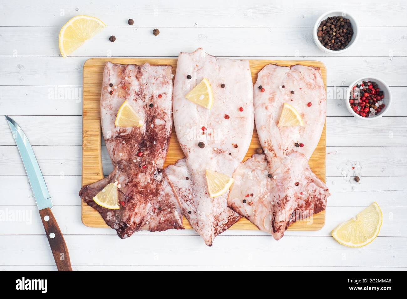 Carcasse de calmar crue avec épices et citron prêt à cuire sur un espace de copie en bois de planche à découper. Vue de dessus Banque D'Images Carcasse de calmar crue avec épices et citron prêt à cuire sur un espace de copie en bois de planche à découper. Vue de dessus Banque D'Images