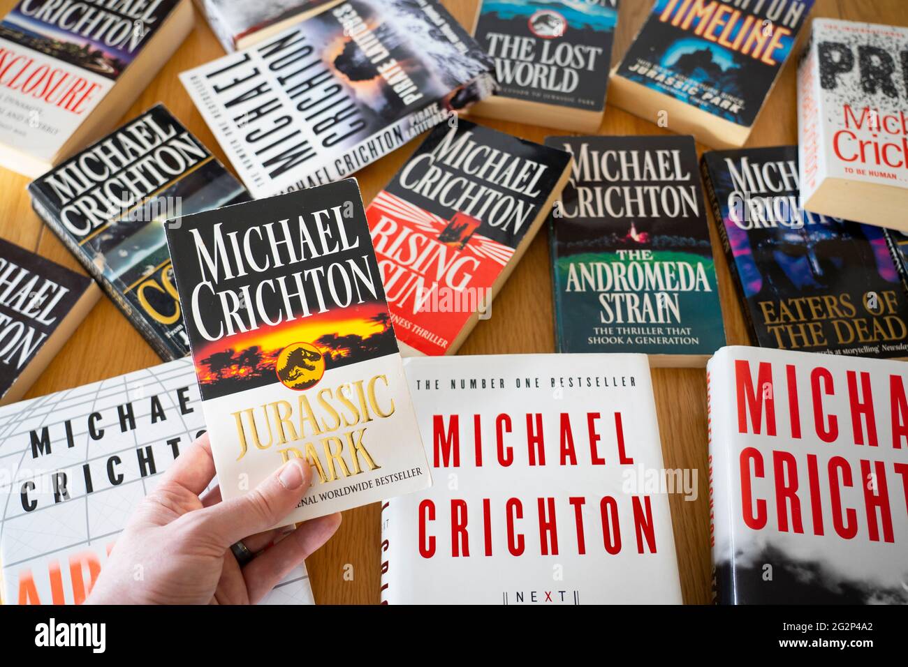 Un homme tient le livre Jurassic Park de l'auteur américain Michael Chrichton, avec d'autres livres de Michael Crichton en arrière-plan Banque D'Images