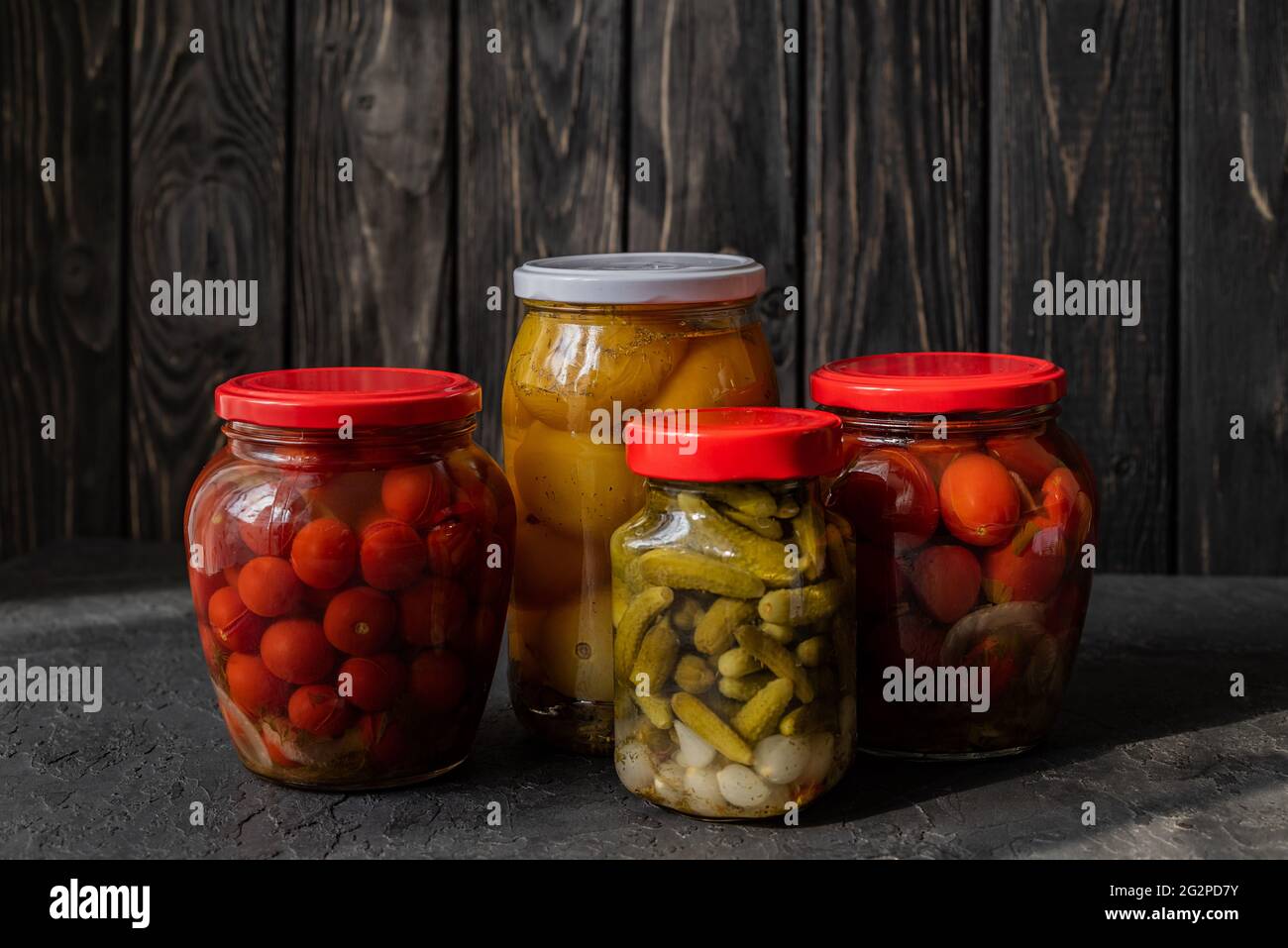 Tomates rouges et jaunes fermentées et concombres sur fond sombre. Plats végétariens. Tomates salées et concombres. Tomates biologiques marinées. Homema Banque D'Images