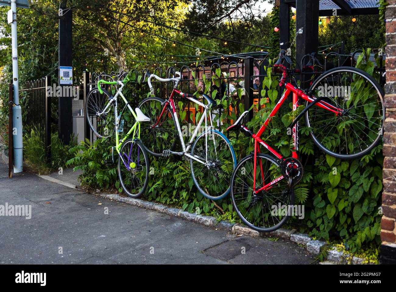 Après l'assouplissement du verrouillage, trois bicyclettes sont verrouillées aux rampes à l'extérieur du jardin d'une maison publique locale (pub), tandis que les propriétaires ont un verre Banque D'Images