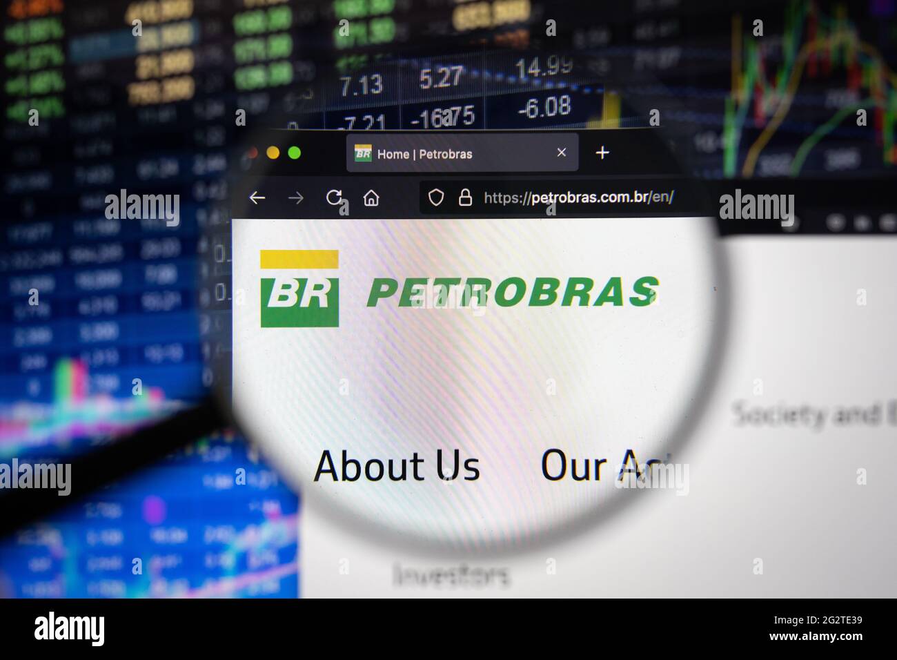 Logo de la société Petrobras sur un site Web avec des développements flous du marché boursier en arrière-plan, vu sur un écran d'ordinateur à travers une loupe Banque D'Images