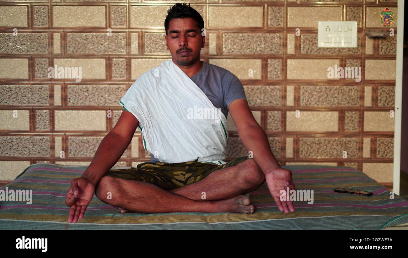 Jeune Indien assis en position Yoga et méditant à la maison. Concept de journée mondiale de yoga. Banque D'Images
