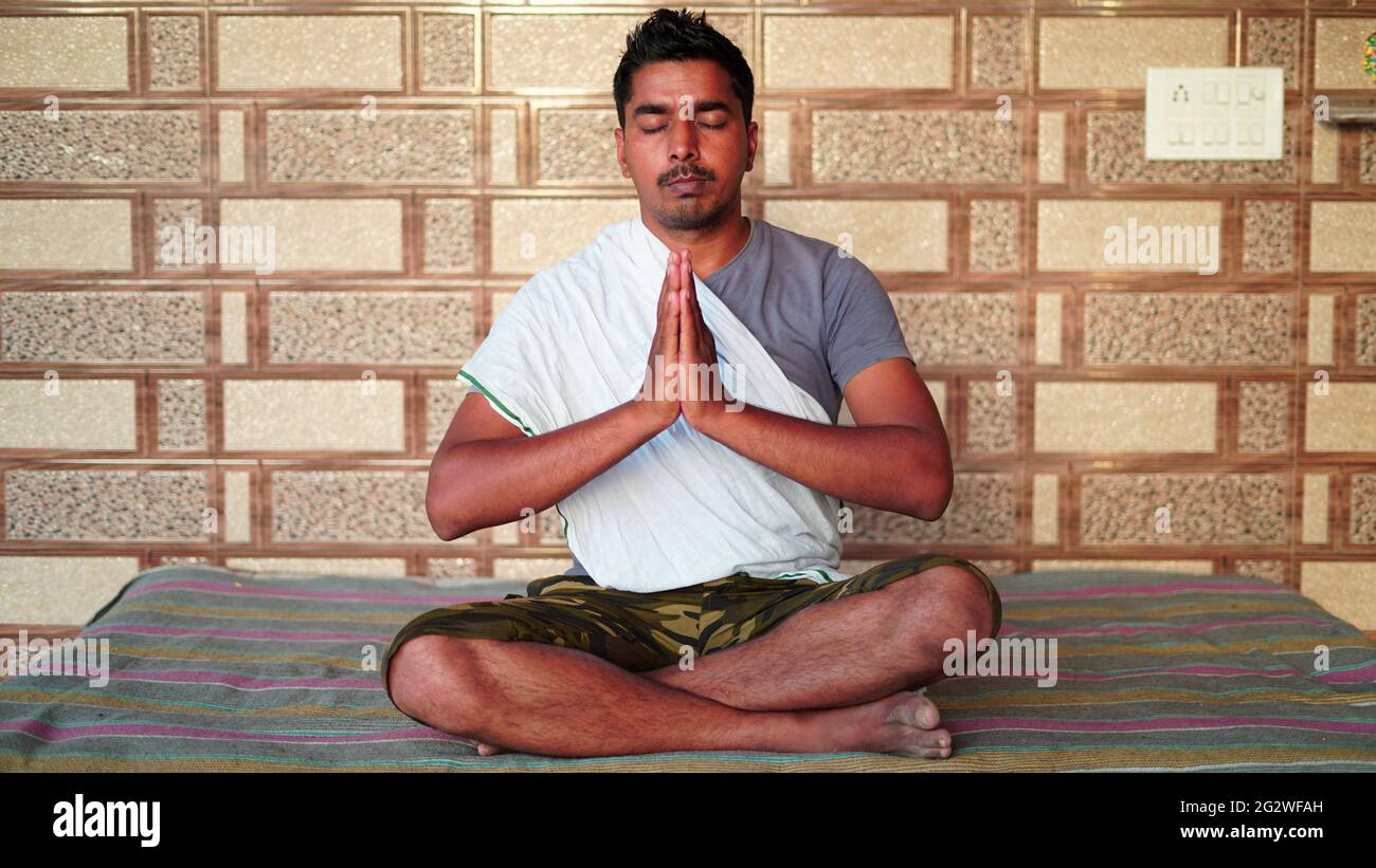 L'homme asiatique fait de la méditation de yoga dans le salon à la maison. Il médite sur le tapis de sol sous le soleil du matin. Banque D'Images