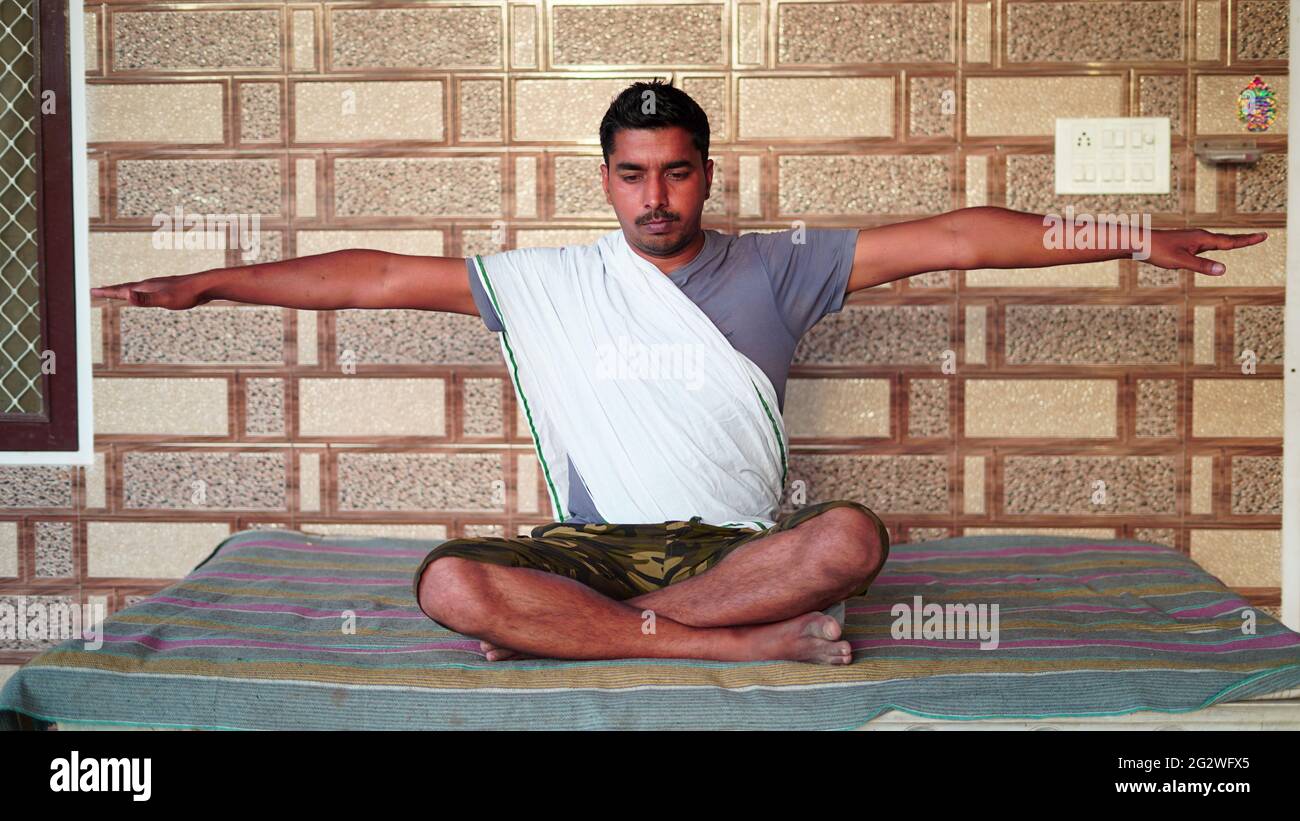 Jeune Indien assis en position de yoga et méditant à la maison. Concept de journée mondiale de yoga. Banque D'Images