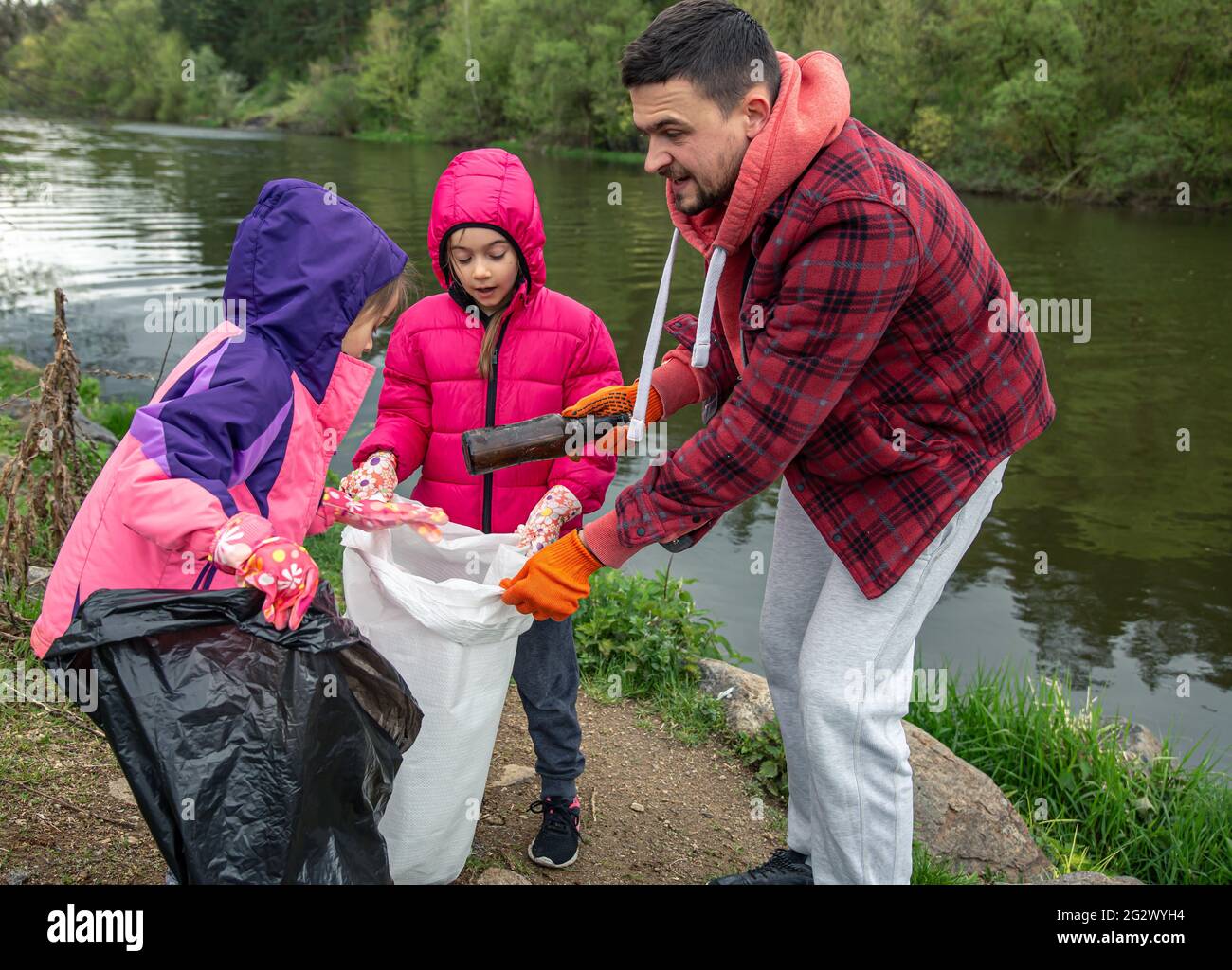 Papa et ses deux petites filles nettoient l'environnement. Banque D'Images