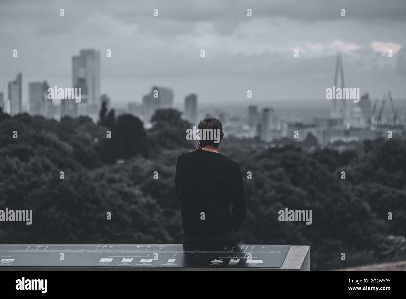 Homme à Hampstead Heath parlant au téléphone et regardant les gratte-ciel de Londres Banque D'Images