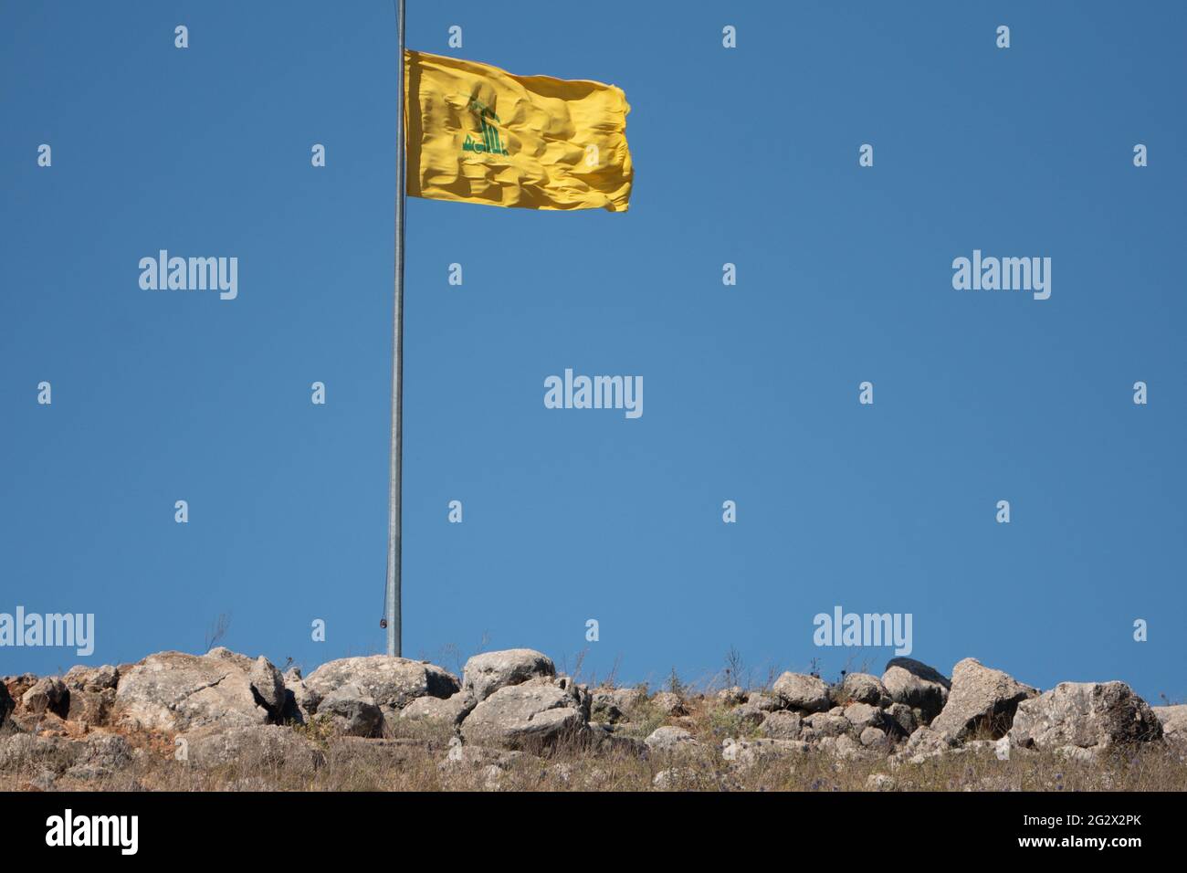 Drapeau jaune du Hezbollah sur fond de ciel bleu à la frontière libanaise israélienne Banque D'Images