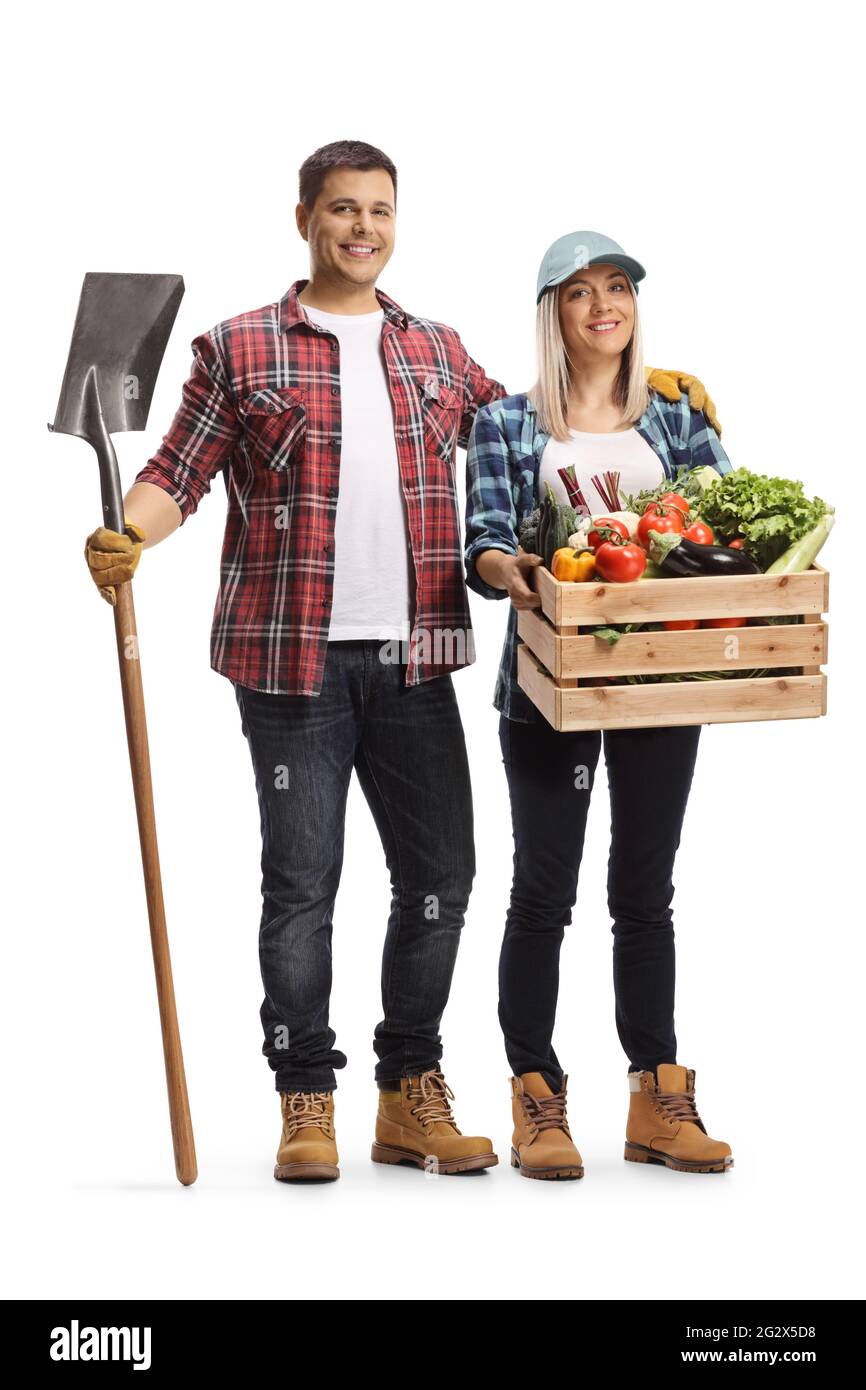 Portrait complet d'un agriculteur mâle tenant une pelle et d'une agricultrice tenant une caisse avec des légumes isolés sur fond blanc Banque D'Images