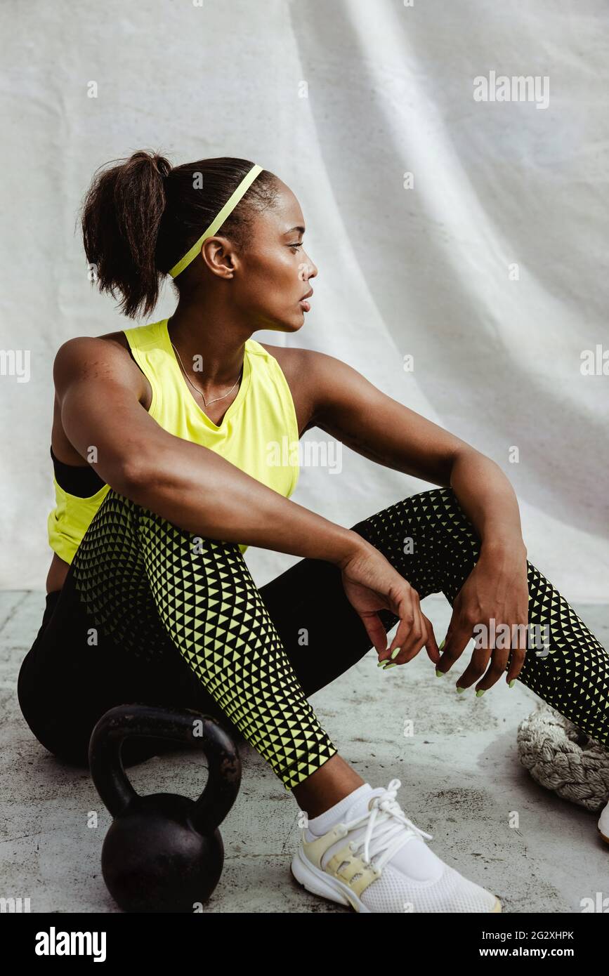 African sportswoman se détendant par le sol. Jeune femme en tenue de sport ayant une pause après l'exercice. Banque D'Images