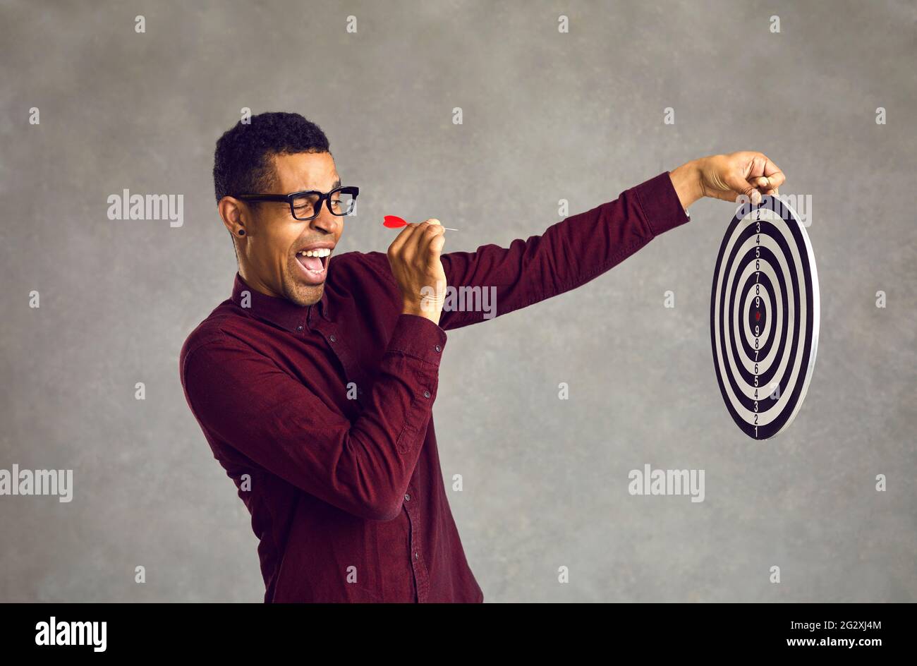 Homme noir confiant visant des fléchettes à la cible de tir cible bullseye comme métaphore pour fixer un objectif d'affaires Banque D'Images