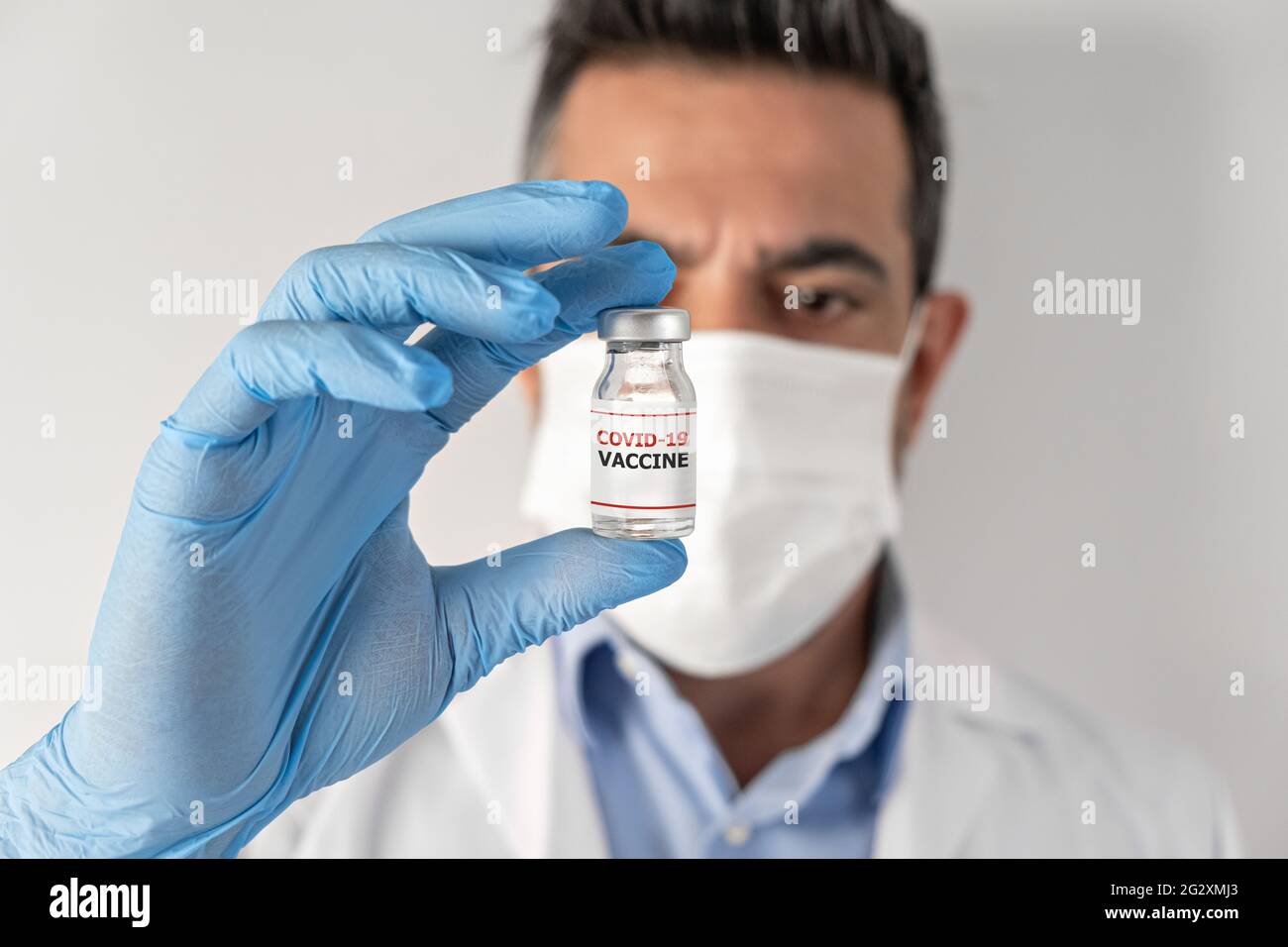 Le médecin en robe blanche et les gants tiennent la seringue en main avec ampoule de vaccins liquides pour la vaccination contre le coronavirus covid-19 Banque D'Images