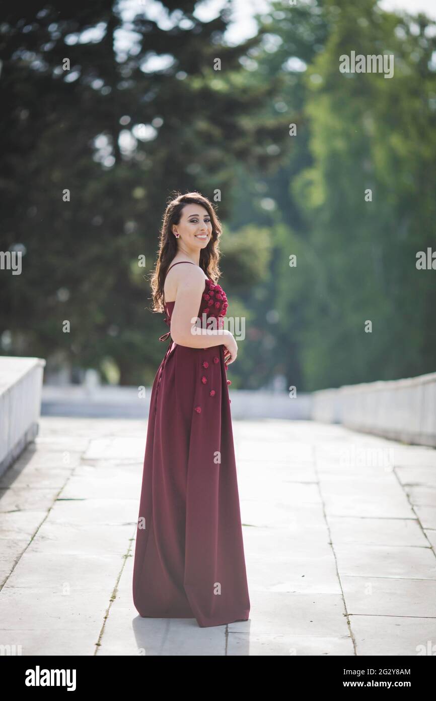 Une jolie femme caucasienne portant une élégante robe longue bordeaux sur  fond de parc Photo Stock - Alamy