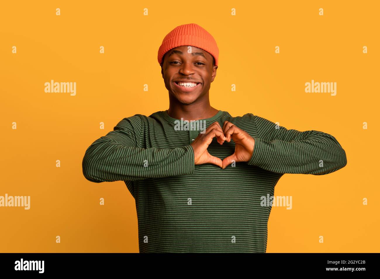 Positif Noir petit homme montrant le coeur geste avec les mains près de la poitrine Banque D'Images