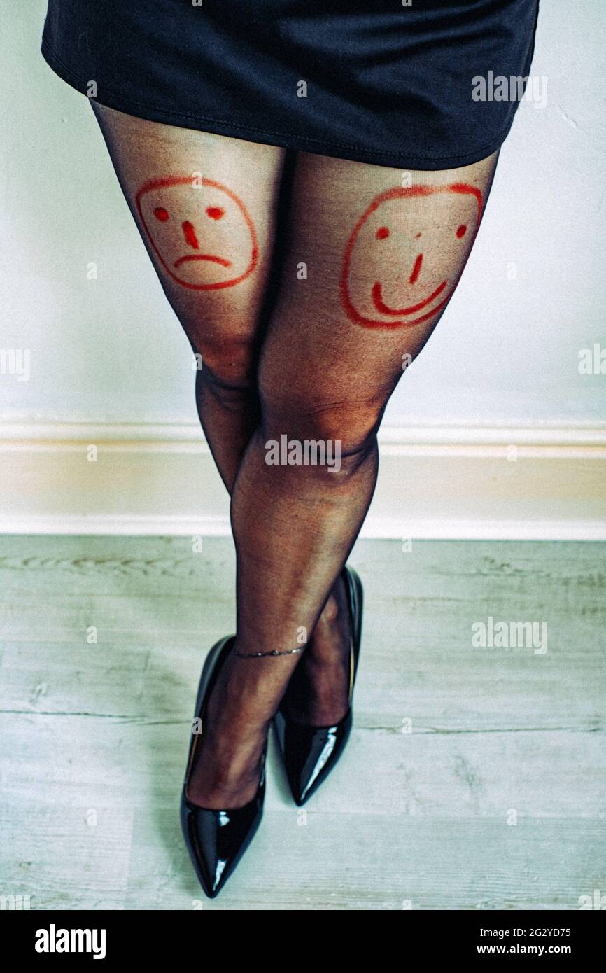 Les visages emoji dessinent sur les jambes de la femme avec un rouge à lèvres Banque D'Images