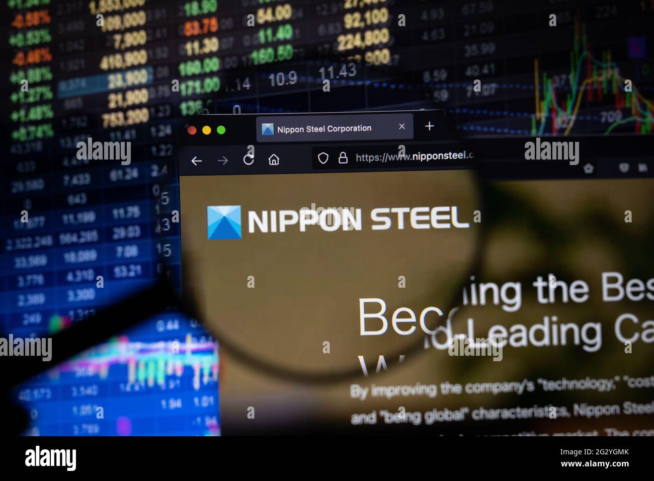 Nippon Steel Company logo sur un site Web avec des développements flous de marché boursier en arrière-plan, vu sur un écran d'ordinateur à travers une loupe Banque D'Images