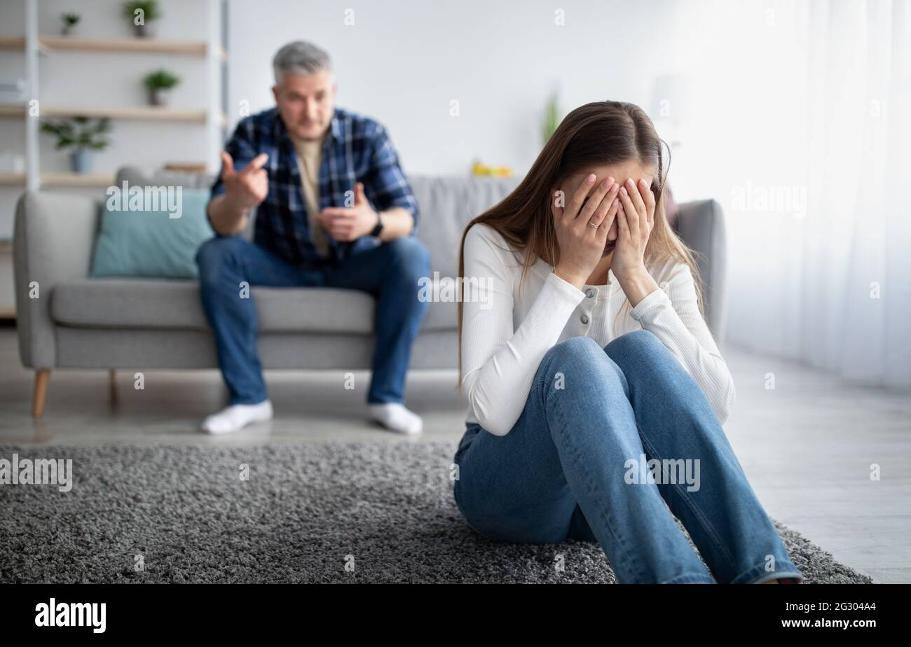 Abus émotionnel dans le concept de mariage. Une femme mûre pleure sur le sol, son mari la blâmant ou l'accusant à la maison Banque D'Images