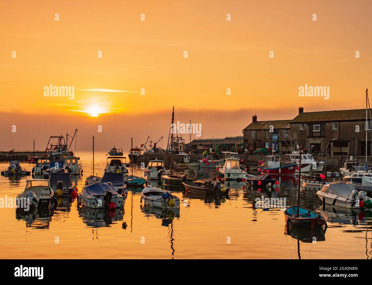 Le ciel brille orange au-dessus du port de Cobb au lever du soleil à Lyme Regis dans Dorset. Scène de la femme du lieutenant français. Copier l'espace Banque D'Images