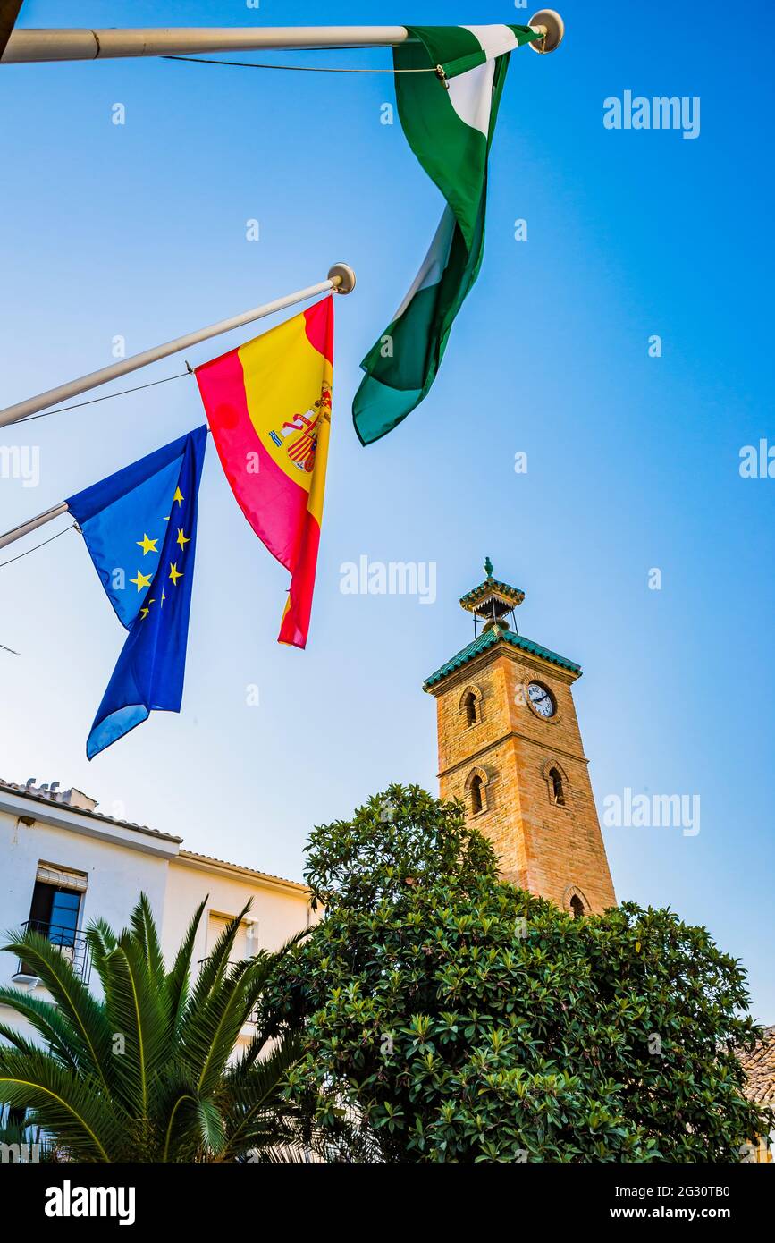 Drapeaux de l'Andalousie, de l'Espagne et de l'Europe, en arrière-plan, la  Tour de l'horloge. Almedinilla est une municipalité espagnole située à  l'extrémité est de la sous-localité Photo Stock - Alamy