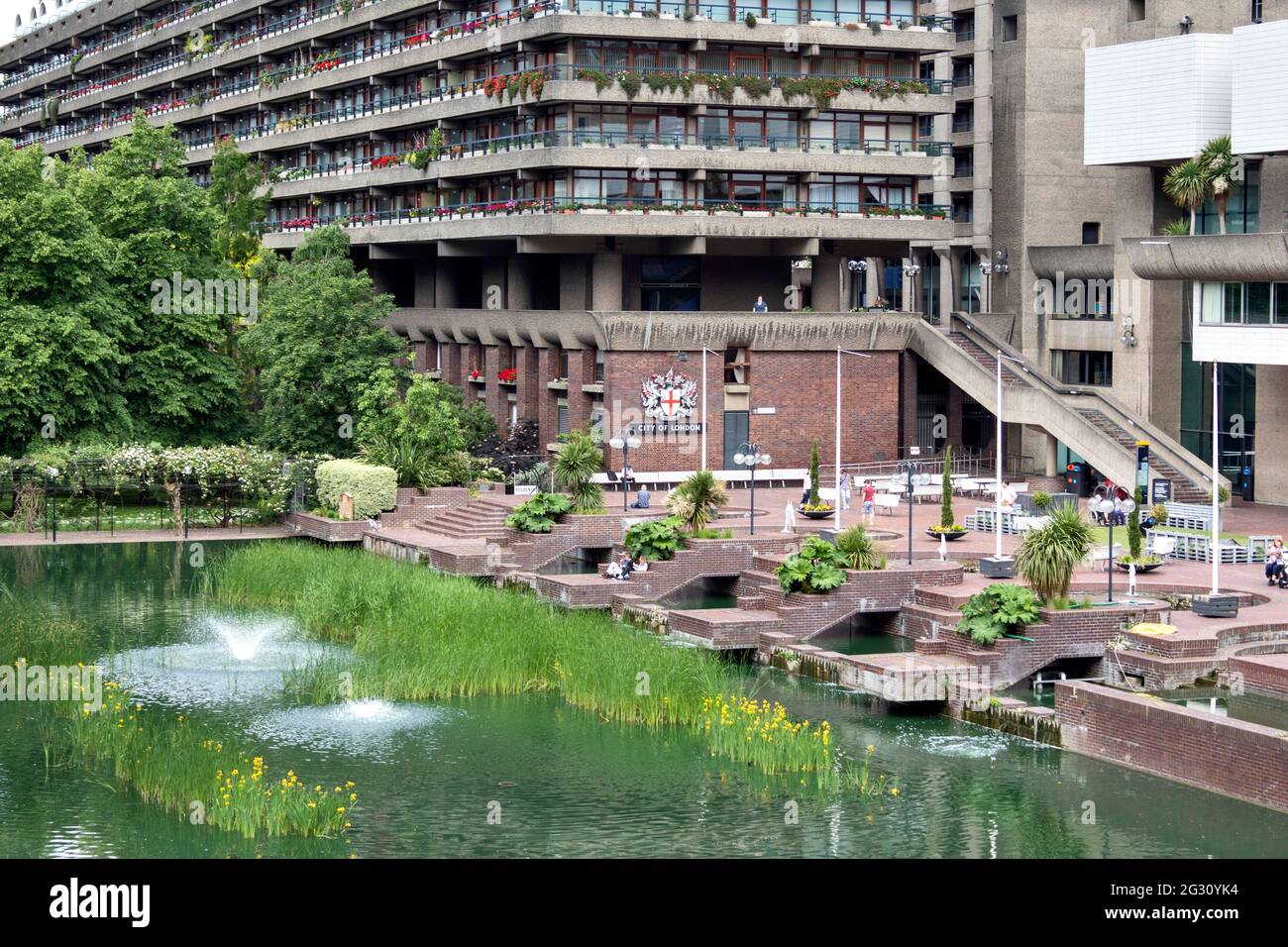 LONDRES ANGLETERRE BARBICAN CENTRE SILK STREET VILLE DE LONDRES LE LAC AVEC DES FONTAINES DE FLEURS JAUNES IRIS ET LA TERRASSE Banque D'Images