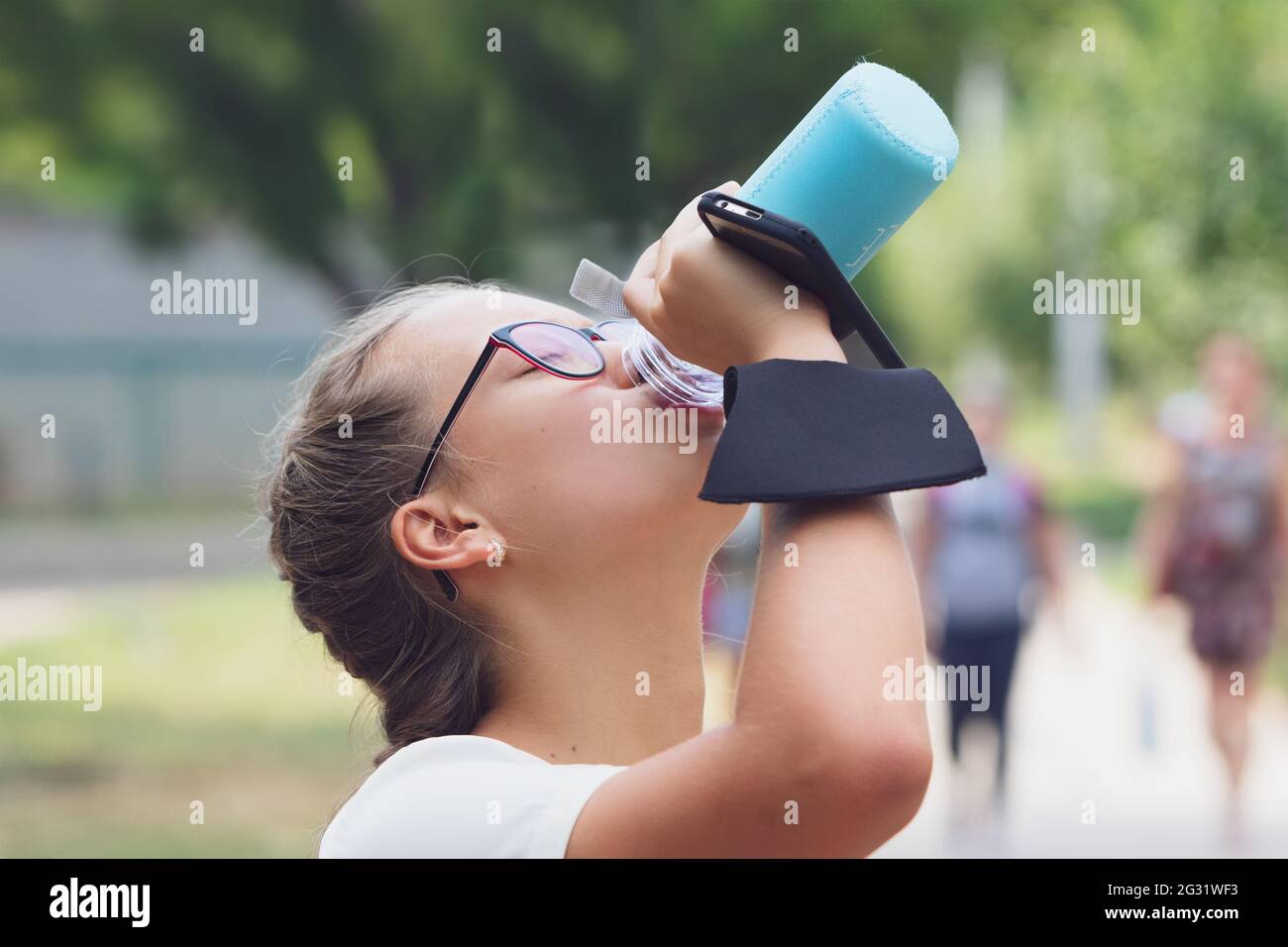 Une adolescente de la rue boit de l'eau. Banque D'Images