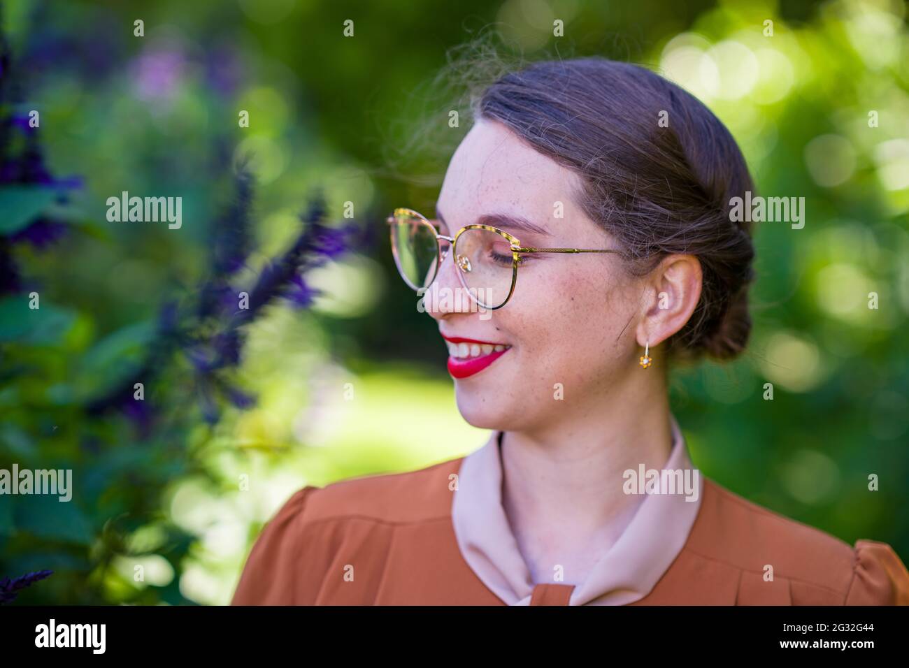 Jeune femme intellectuelle vêtue de vêtements des années 1940 dans un jardin Banque D'Images