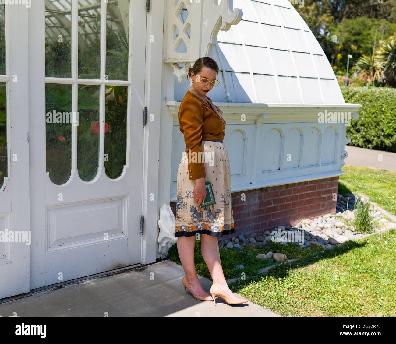 Jeune femme dans la mode des années 1940 debout devant le Conservatoire victorien Banque D'Images