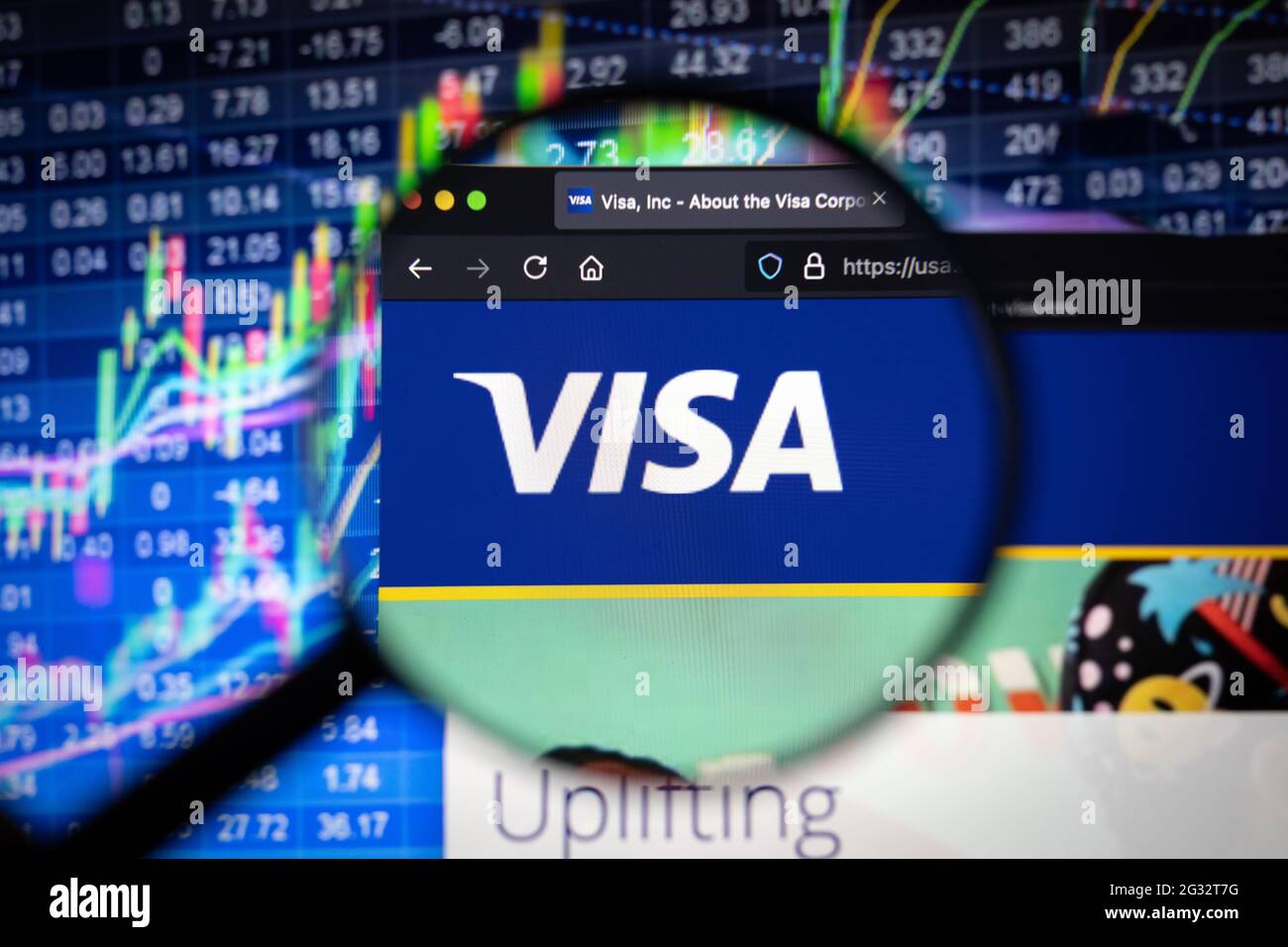 Le logo de la société Visa sur un site web avec des développements flous du marché boursier en arrière-plan, vu sur un écran d'ordinateur à travers une loupe Banque D'Images