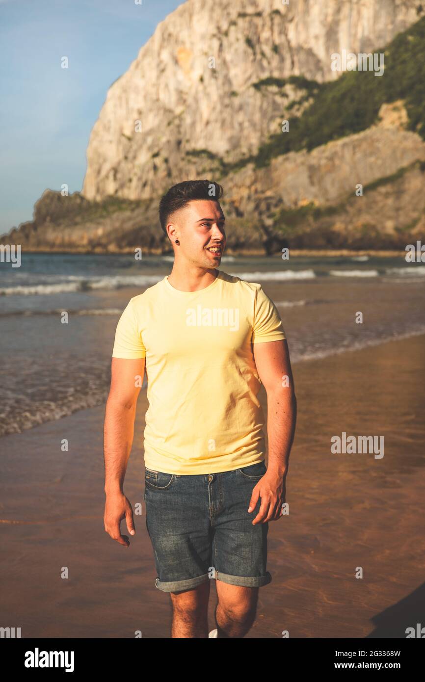 Jeune homme de race blanche marchant à la plage Banque D'Images