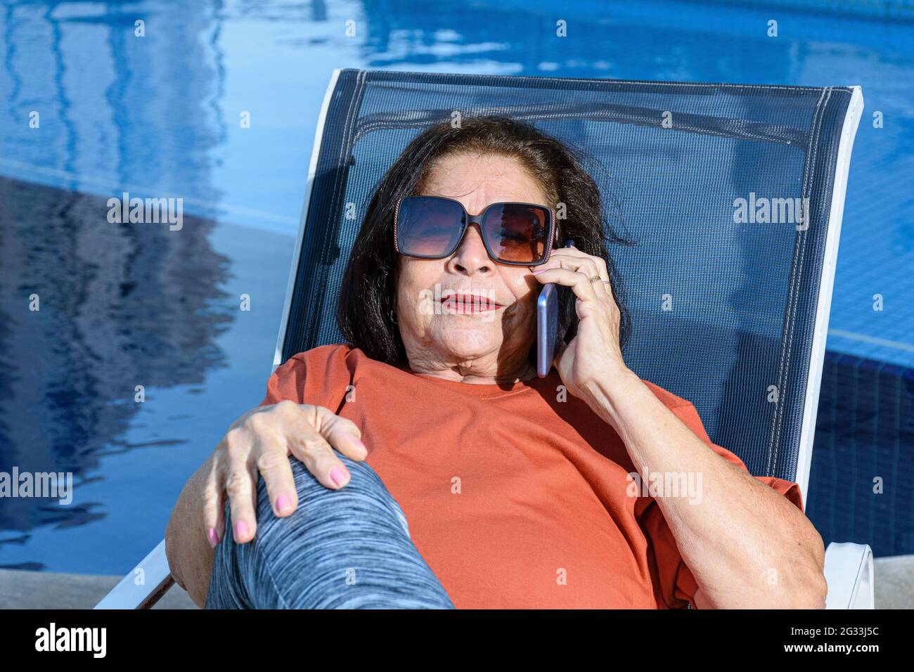Gros plan d'une femme de 74 ans avec des lunettes de soleil assises et répondant à un appel. Banque D'Images