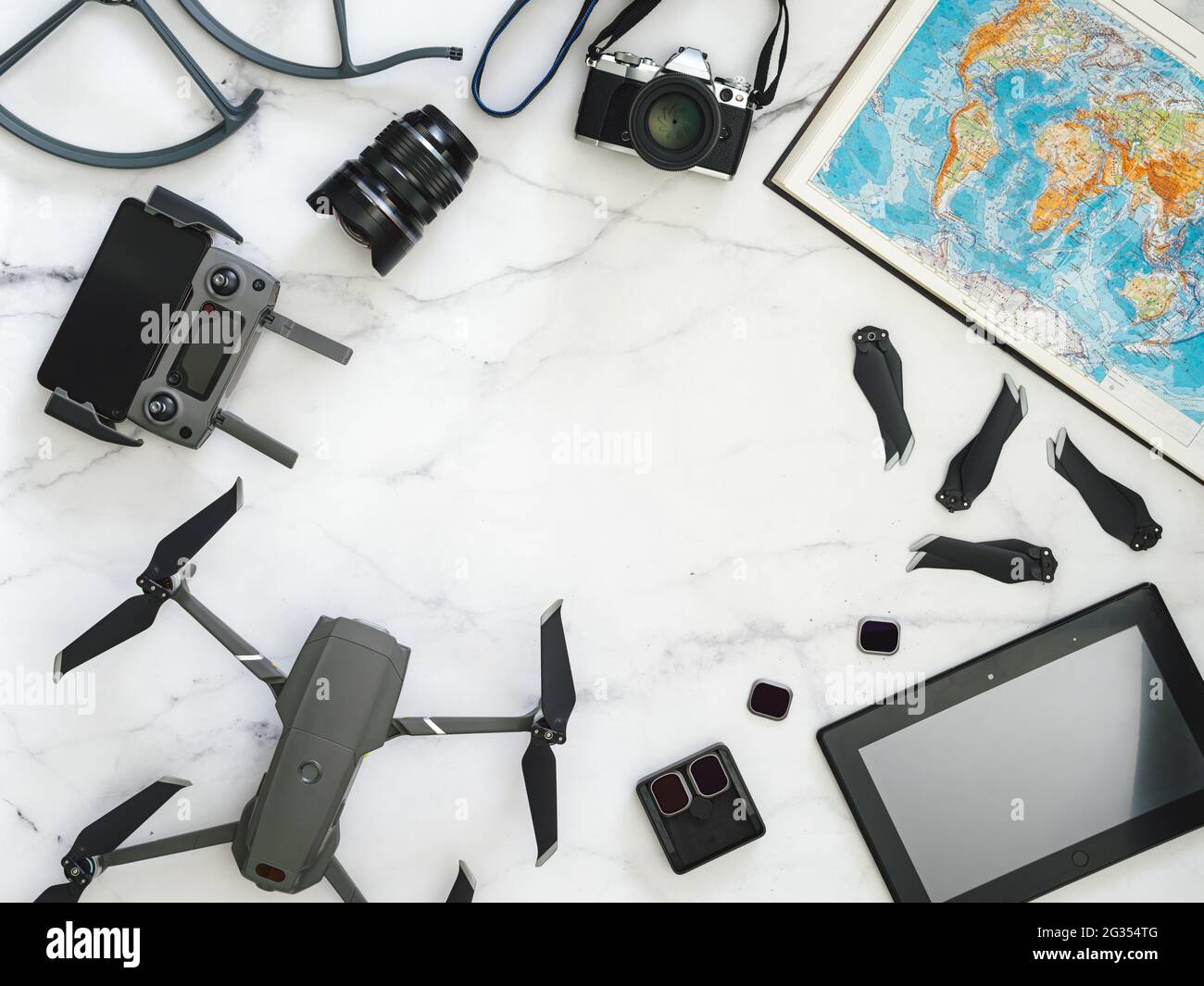 Concept de voyage avec drone pliable, appareil photo sans miroir, tablette, carte du monde, accessoires, copier l'espace au centre. Vue de dessus ou plan de travail. Banque D'Images