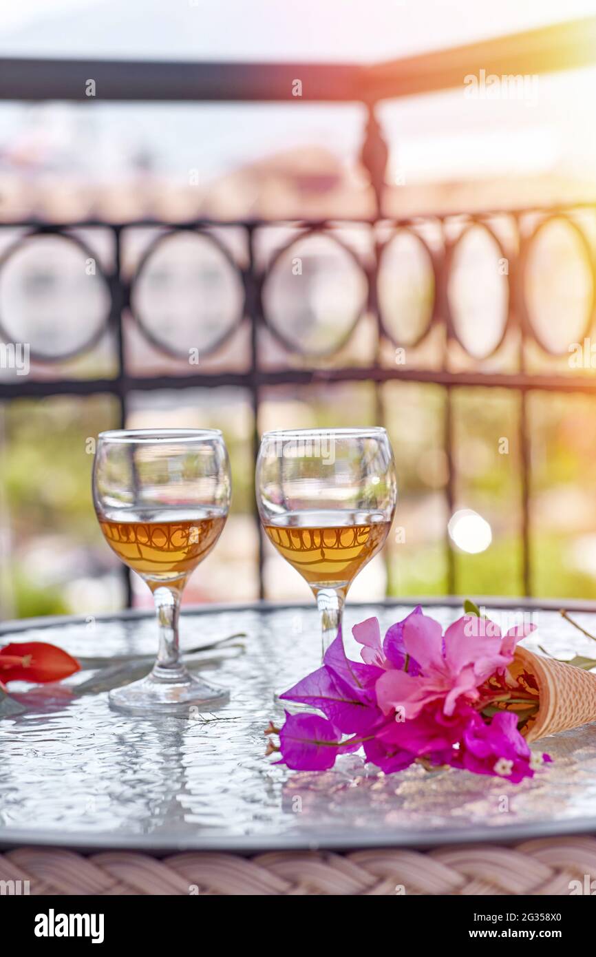 Gros plan de la glass de vin avec des fleurs roses de bougainvilliers sur une table en verre. Concept de rafraîchissement. Fleurs surréalistes d'été. Arrière-plan ensoleillé en été. Photo de haute qualité Banque D'Images