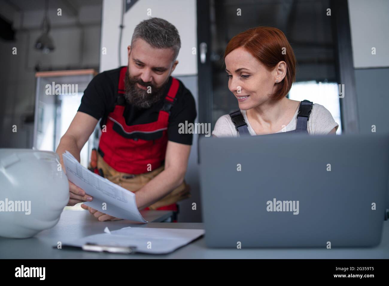 Des travailleurs ou des ingénieurs de l'industrie avec un ordinateur portable à l'intérieur de l'usine, discutant des problèmes. Banque D'Images