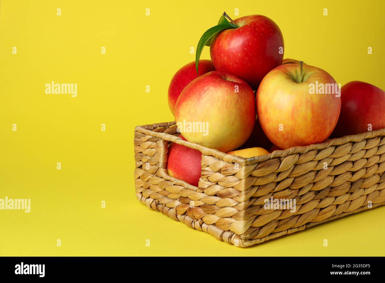 Panier avec pommes rouges sur fond jaune Banque D'Images