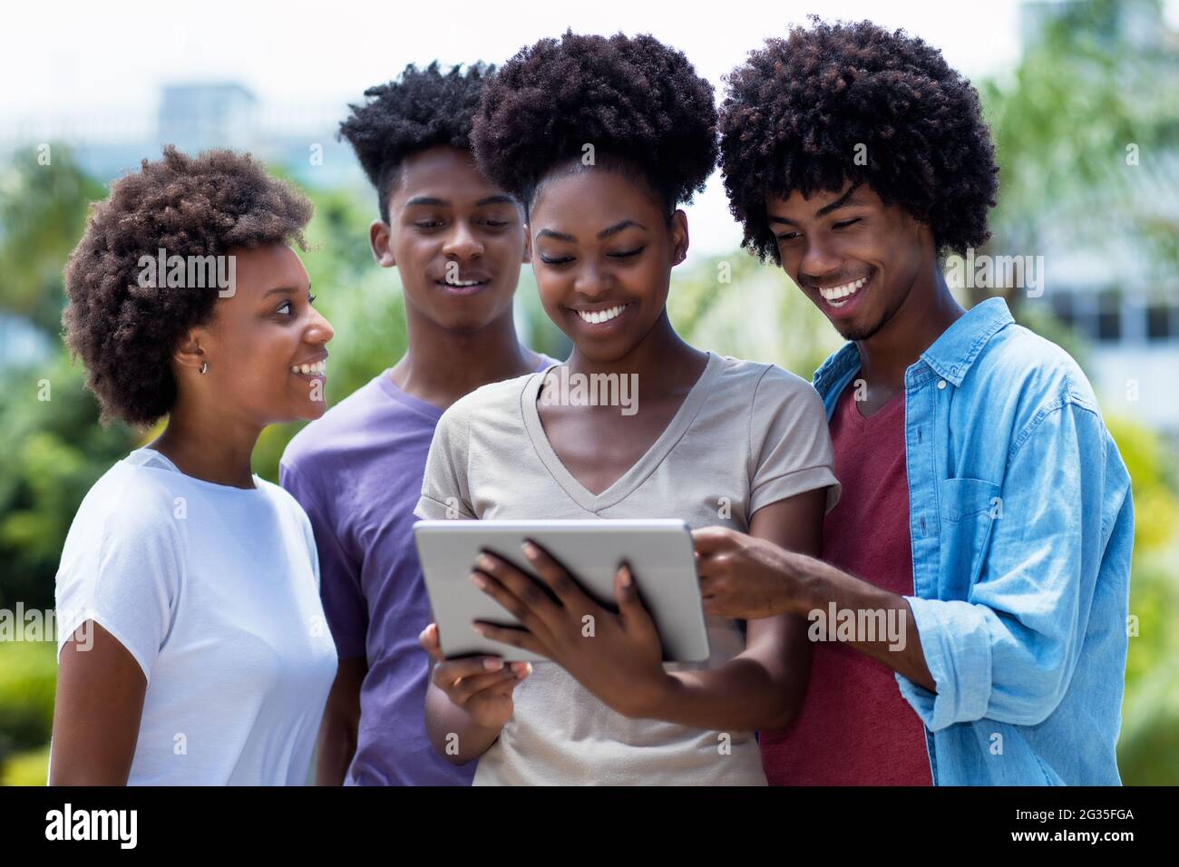 Étudiants afro-américains avec tablette numérique regardant des clips vidéo en ligne en plein air en été dans la ville Banque D'Images