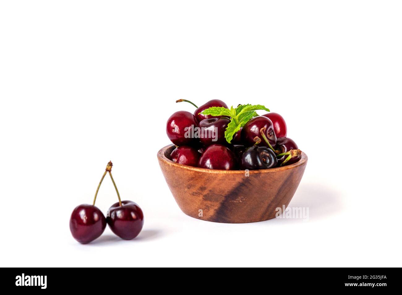 Cerise dans un bol en bois isolé sur blanc. Concept d'alimentation saine. Mise au point sélective. Banque D'Images