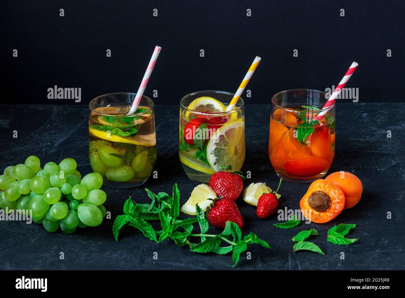 Boissons saines d'été, limonade en verres avec paille sur fond noir. Banque D'Images