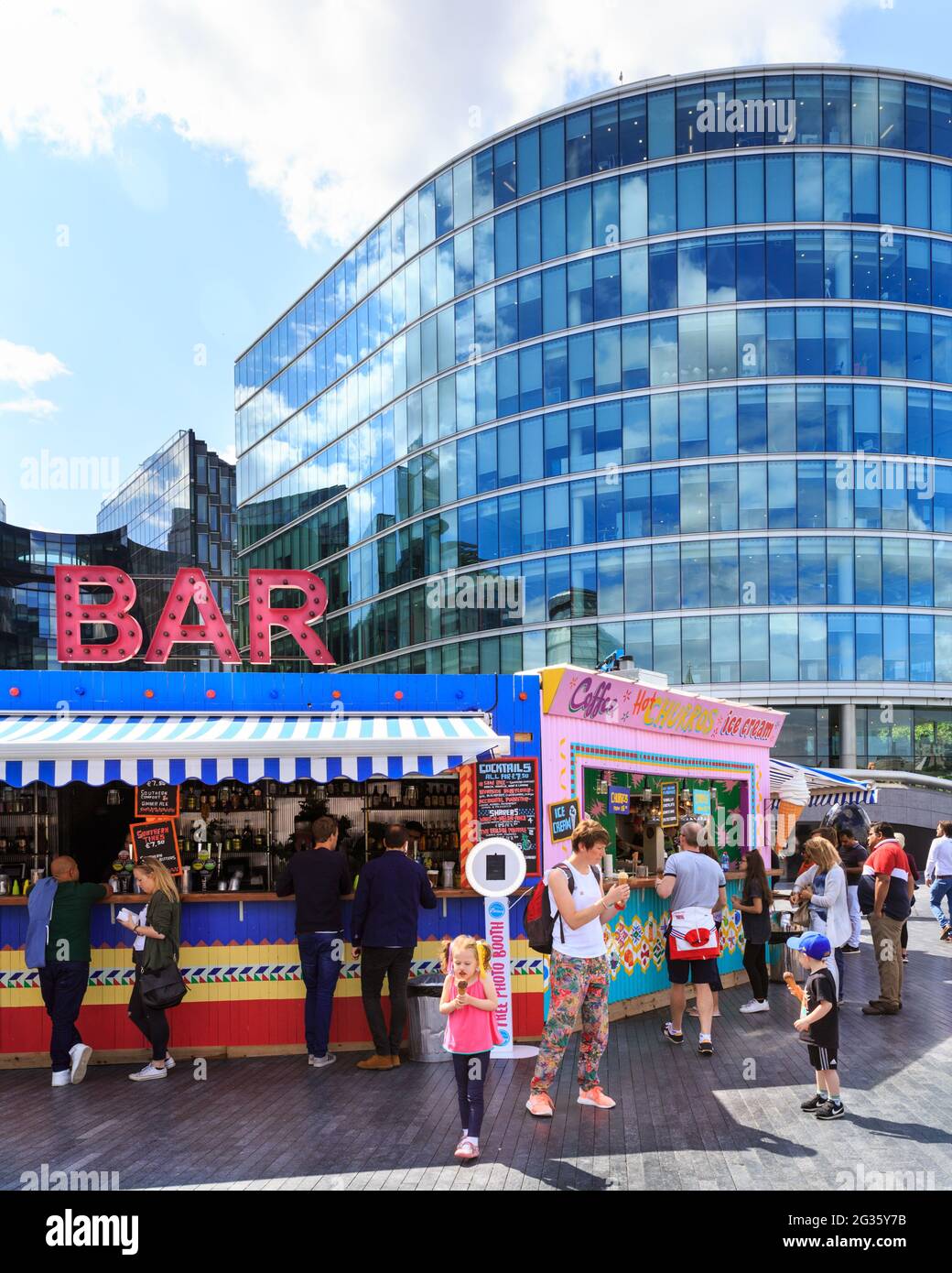Les gens achètent des boissons dans un bar extérieur pop up à More London en plein soleil d'été avec Tower Bridge et City Hall en arrière-plan, Londres, Angleterre Banque D'Images
