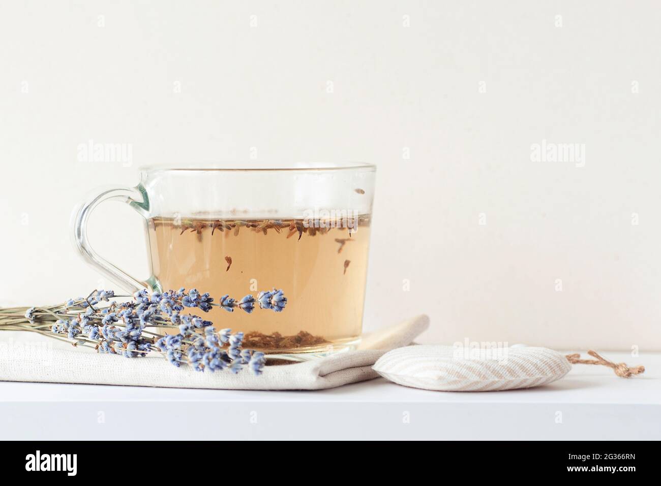 Tasse en verre avec thé chaud lavande et bouquet lavande sur un bureau de cuisine blanc, espace pour le texte Banque D'Images