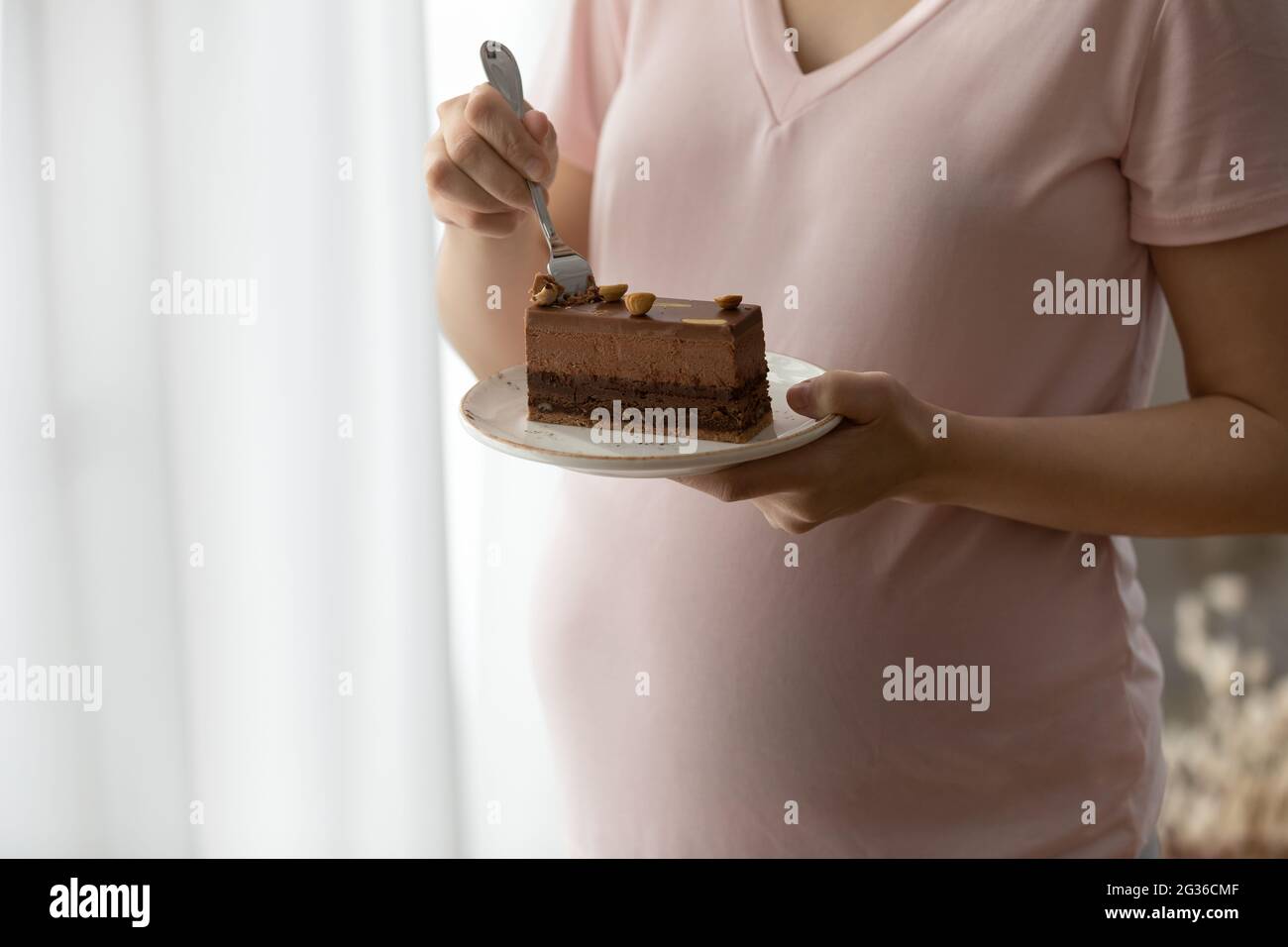 Gros plan sur une femme enceinte en train de manger un gâteau au chocolat Banque D'Images