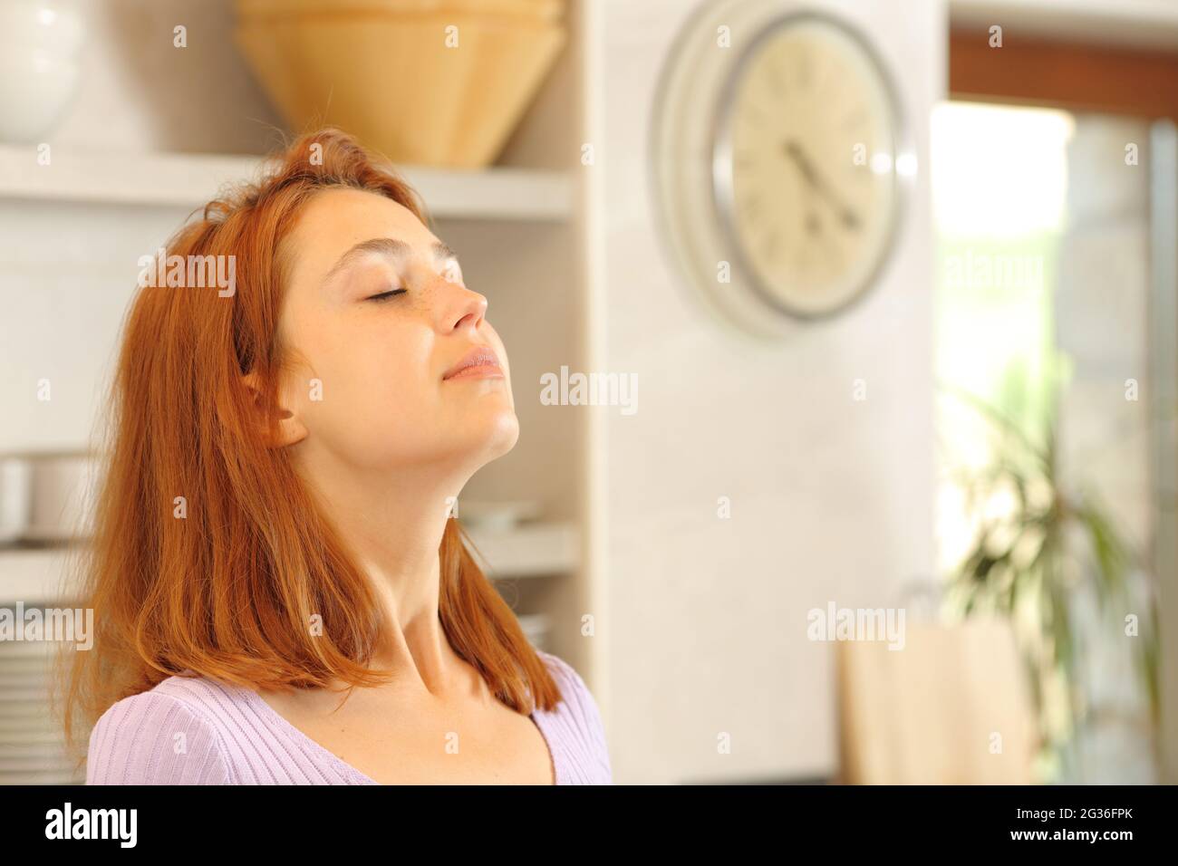 Une femme satisfaite respire de l'air frais dans la cuisine à la maison Banque D'Images