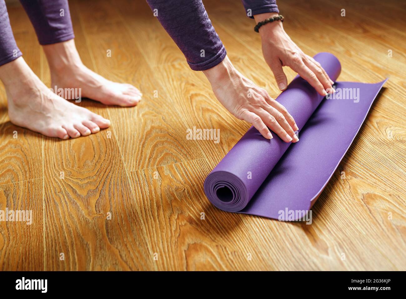 Une femme pose un tapis de yoga lilas sur le parquet. Femmes pratiquant le  yoga. Un mode de vie sain et isolé Photo Stock - Alamy